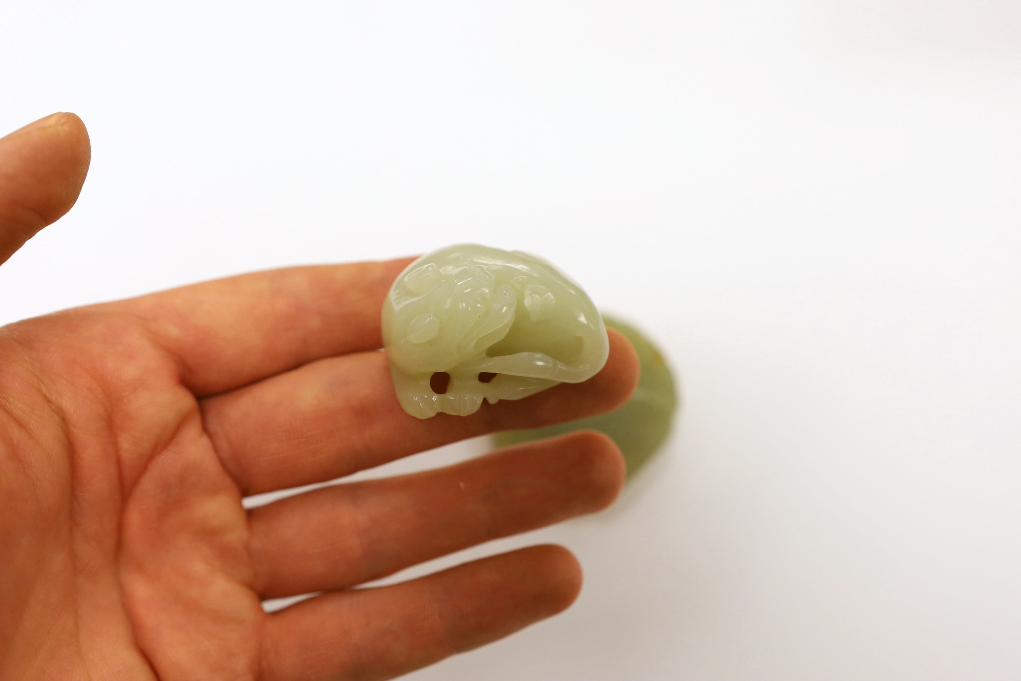 A Chinese carved jade pendant and another carving of a recumbent lion dog, largest 5cm